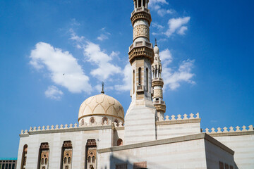 Obraz premium A stunning view of a mosque against a vibrant blue sky. The architectural details are exquisite. Majestic Mosque Under a Clear Blue Sky.
