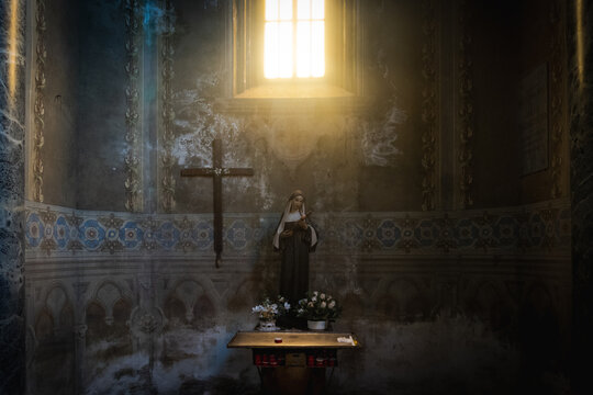 Illuminated altar with statue of a saint and cross in spiritual setting.