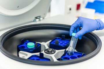 Scientist placing test tube in laboratory centrifuge for medical research 