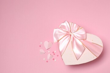 Beautiful gift box with pink hearts on color background