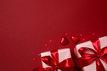 Beautiful gift boxes with red hearts on color background