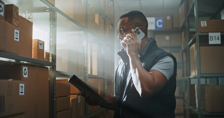 African American Logistics Coordinator with Tablet Computer Chats with Customer on Call Using...