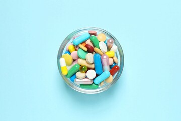 Various pills in a bowl on color background