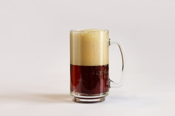 Kvass in a glass, light background. Glass of dark beer or kvass with foam in a glass on a light gray background. Traditional beer mug with a handle. Close-up on a glass with a cool tasty drink