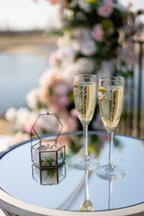 two champagne glasses on the table on the background of water near the arch Festive background for the wedding