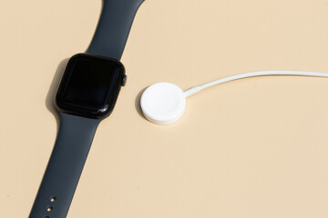 A modern smart watch with its magnetic charger neatly placed on a table, showcasing a sleek and minimalist charging setup.