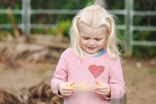 Happy little girl playing with slinky toy in the garden