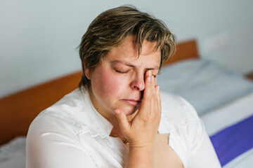 Sad woman crying and touching her face at home