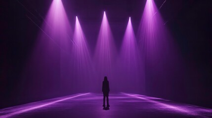 Silhouette of a person standing in a dark room illuminated by purple spotlights.