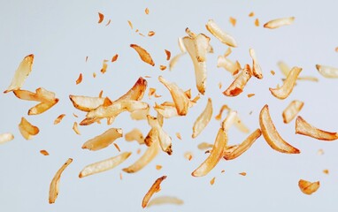 Fototapeta premium Flying French fries scattered in mid-air, golden and crispy, floating gracefully against a clean white background