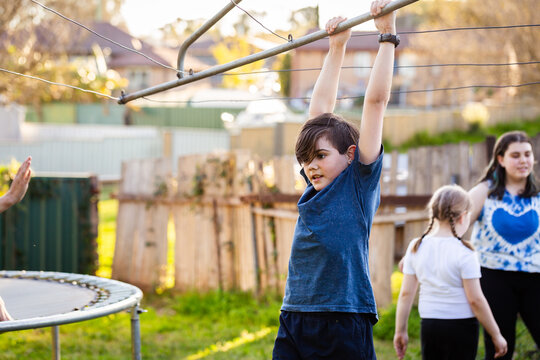 First Nations Australian kid swinging on hills hoist rotary clothesline in Aussie backyard