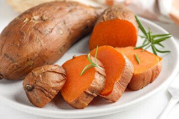 Tasty cooked sweet potatoes and rosemary on table, closeup