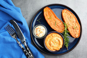 Halves of tasty baked sweet potato served on grey textured table, flat lay