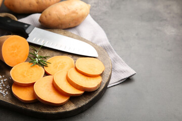 Fresh raw sweet potatoes, spices and knife on gray table, closeup. Space for text