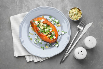 Tasty cooked sweet potato with feta cheese, pumpkin seeds and green onion on grey table, top view