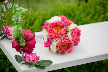 A white swing with a bouquet of pink and white flowers on it. The flowers are arranged in a way that creates a sense of balance and harmony. The swing itself is a symbol of relaxation and leisure