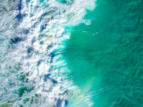 An aqua blue wave crashing over crystal clear water