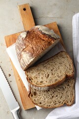 Cut loaf of fresh bread and knife on table, top view