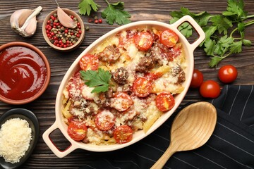 Delicious pasta casserole with cheese, tomatoes and minced meat in baking dish served on wooden table, flat lay