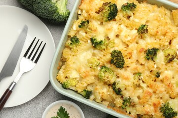 Tasty pasta casserole with cheese, broccoli and sauce on grey table, flat lay
