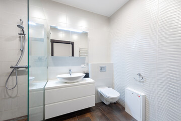 Modern, bright bathroom with white tiles, a sleek sink and toilet, and a glass shower enclosure. Home Interior