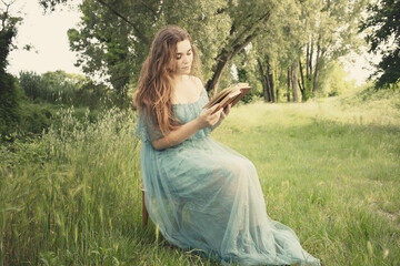 elegant woman sitting in a meadow reading a book