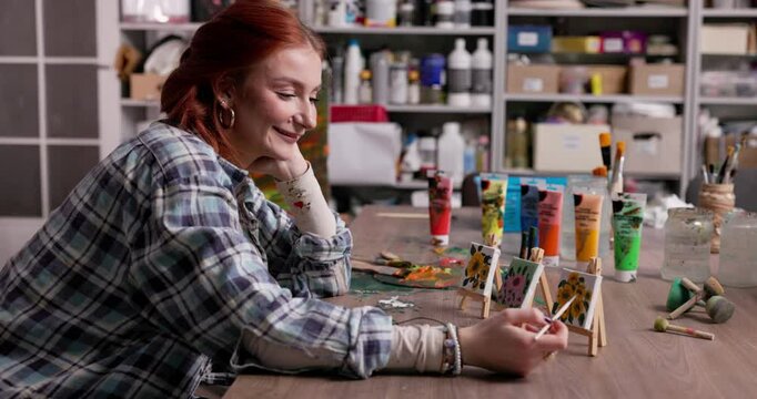 A Young Artist Deep in Thought, Contemplating Her Vibrant and Colorful Paintings in Her Studio