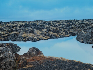 Obraz premium A stunning view of the Blue Lagoon in Iceland, showcasing its iconic milky blue geothermal waters surrounded by rugged volcanic rocks. The misty atmosphere 
