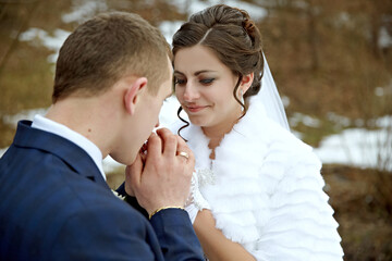 A bride and groom are shaking hands, with the bride wearing a white fur coat. The bride is wearing a wedding ring