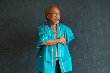 Elderly man with pain and illness standing on black wall background