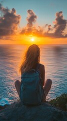 Fototapeta premium A solo traveler sits peacefully on a rock, gazing at the vibrant sunset casting hues over the ocean. With a backpack beside, they embrace the tranquility and beauty of nature