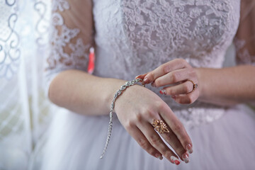 A woman is wearing a bracelet and ring. She is adjusting the bracelet on her wrist. The bracelet is silver and has a butterfly design. The woman is wearing a white dress and has her hands on her hips