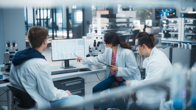 Modern Medical Laboratory: Scientists Working Together on a Research Project. Two Young Men and a Female Talking About Vaccine Development Methods, Gene Editing Studies, Biotechnology Breakthroughs