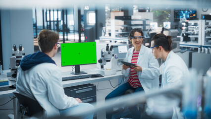 Employees Looking at a Computer with Green Screen in a Science Laboratory. Female Research...