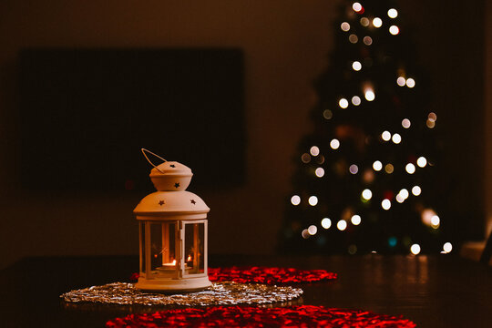 Small indoor lantern with Christmas tree in background creating bokeh light effect
