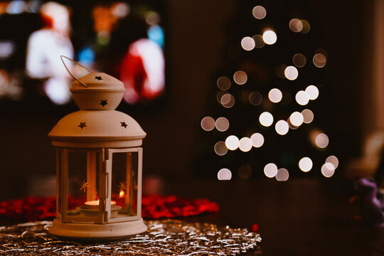 Small indoor lantern with Christmas tree in background creating bokeh light effect
