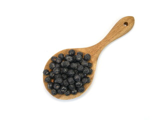 Aronia berries in a wooden spoon isolated against white background. Black chokeberry or aronia berries, isolated on white background, can be used to make wine, jam, syrup, juice, soft spreads