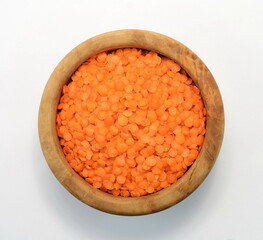 Red lentils in a wooden bowl isolated on white background. Red lentils pile isolated. Dry orange lentil grains, round heap of dal, spilled raw daal, dhal, masoor on white 