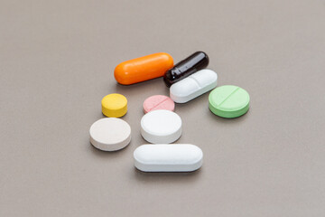 An assortment of medicine pills in various colors spread across a brown table, symbolizing healthcare and pharmaceuticals.