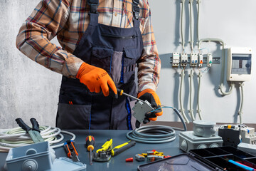 Electrician working at electric panel. Installing, repairing electrical system.