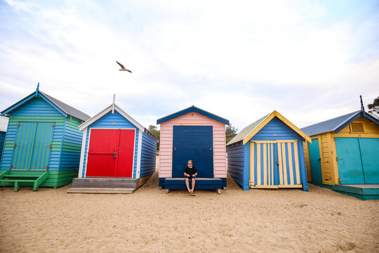 Row of vibrant beach huts with young boy sitting at centre