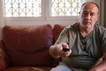 Retired man sad and bored watching television at home