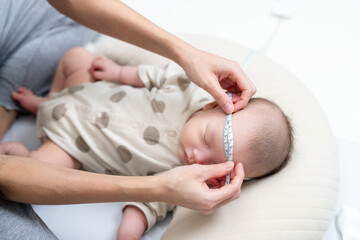 Newborn baby head measurement by caring mother hands