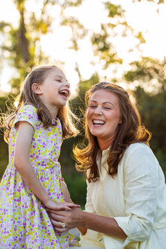 Joyful portrait of happy smiling mother and young daughter in golden light outdoors