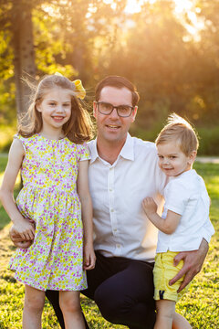 Portrait of dad with son and daughter standing in golden yellow evening light outdoors