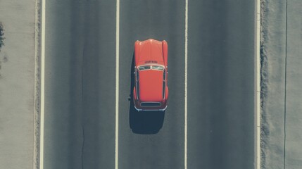 Aerial view of a classic red car driving on a highway.