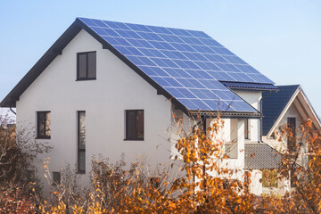 Solar Panels in Autumn. Modern Home with Solar Panels and Autumn Trees. Solar Panels of Energy Efficient House Roof among Fall Landscape. Alternative energy, Saving resources.