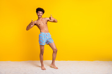 Young man enjoying summer vacation at the beach with yellow background, wearing swimwear and expressing happiness.