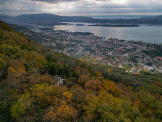 Fototapeta premium Aerial view of abandoned ancient stone church ruins hidden in autumn forest on a mountain slope above Tivat, Montenegro 