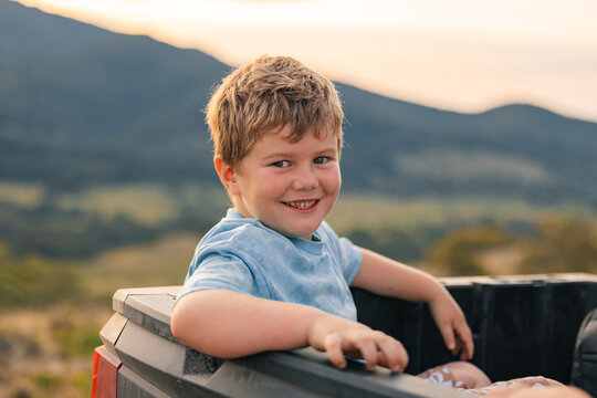 Little boy sitting in back of off-road buggy on farm